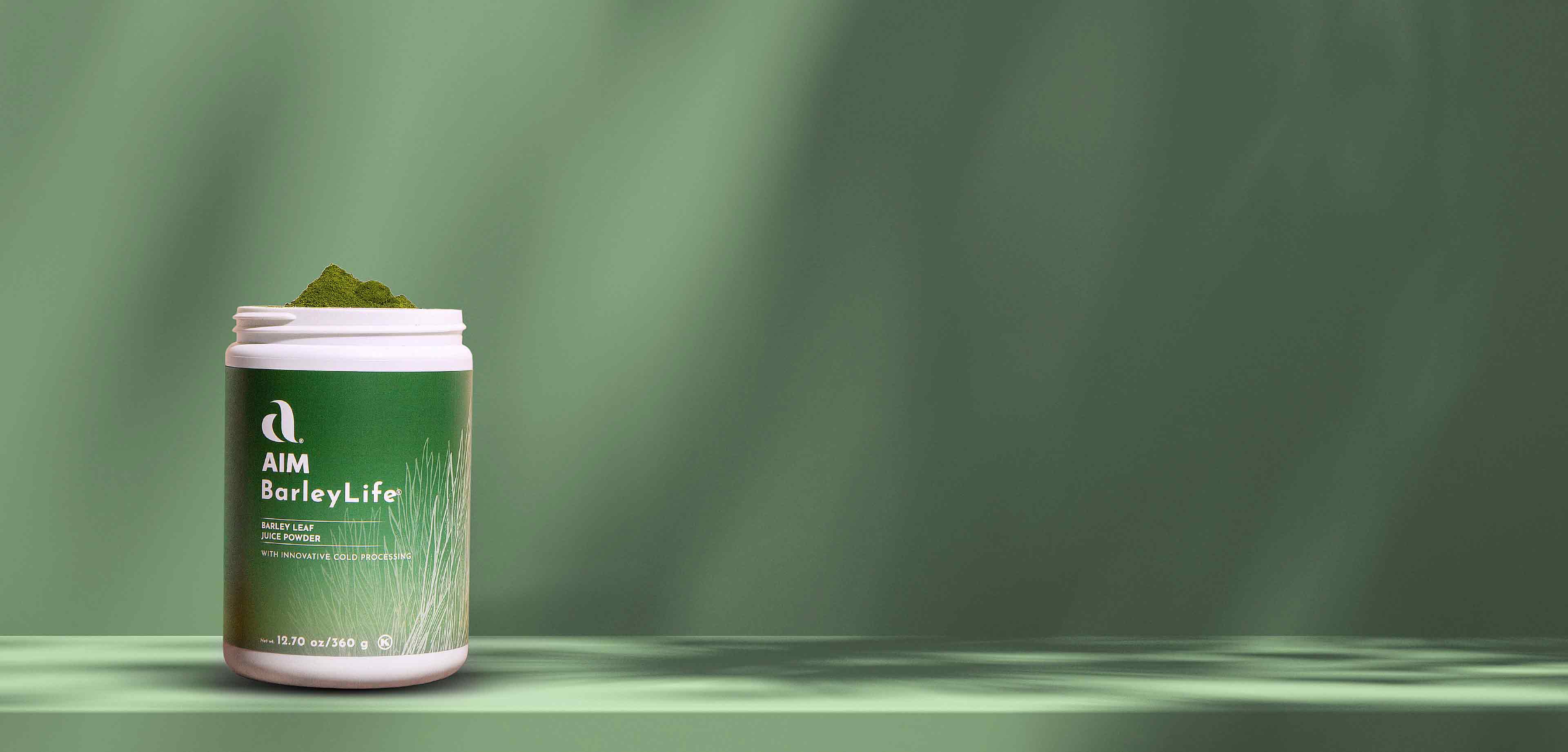 A picture of an open container of BarleyLife overflowing with green barley leaf juice powder in front of a light green background illuminated by diffuse rays of light.  Overlaid text says 'BarleyLife.  Nourish your body with the goodness<br />of our whole food nutrition.' Followed by a Shop Now button.